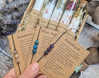 Può includere: Un set di sei piccoli flaconi di vetro riempiti con sali da bagno e cristalli. Ogni flacone ha un'etichetta con il nome di una gemma diversa e le sue proprietà. Le gemme sono Sunstone, Apatite blu, Ametista e altro ancora. I flaconi sono disposti in una scatola di legno.