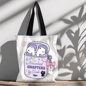 A cute Halloween bookish png tote bag mockup of a haunted themed earbuds case for readers who love audiobooks. The case has the text "Haunted Chapers Club". The case is decorated with a pink bow, ghosts, sparkles, a bat, black cat, candle, book and the moon.
