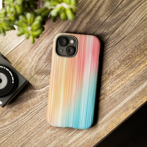 May include: A phone case with a colorful abstract design featuring vertical stripes in shades of pink, orange, yellow, blue, and green. The case has a cutout for the phone's camera.