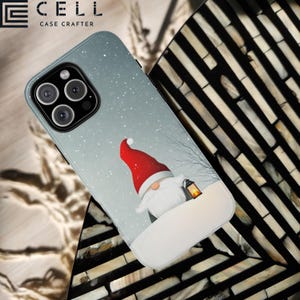 May include: A phone case with a winter scene featuring a gnome wearing a red hat and holding a lantern. The background is a snowy landscape with a light blue sky. The case is designed for an iPhone 12 Pro Max.
