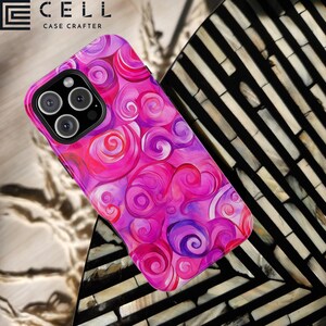 May include: A phone case with a swirling design in pink, purple, and red hues. The case has a glossy finish and a camera cutout. The brand name "CELL CASE CRAFTER" is displayed in the top left corner. The design resembles a watercolor painting.