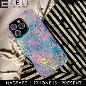 May include: A holographic iPhone case with a colorful, iridescent design. The case features a textured surface with abstract lettering and a MagSafe design. The phone case is designed for iPhone 13 models and newer.