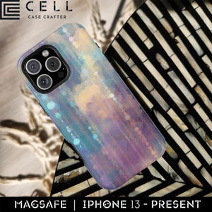 May include: A smartphone case with a colorful, iridescent design. The case has a pattern of small circles and lines in shades of blue, purple, and yellow. The text "MAGSAFE | IPHONE 13 - PRESENT" is at the bottom. The brand logo "CELL CASE CRAFTER" is at the top.