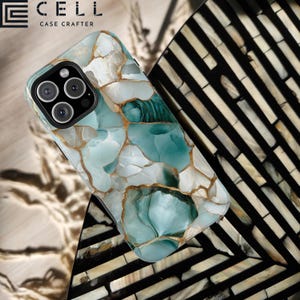 May include: A phone case with a marble-like design featuring blue, white, and gold accents. The case has a raised camera bump and a cutout for the phone's charging port.