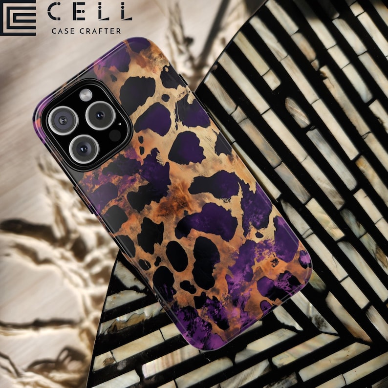 May include: A black phone case with a leopard print design in shades of purple, brown, and gold. The case has a raised camera bump and the text "CELL CASE CRAFTERS" is printed on the top.