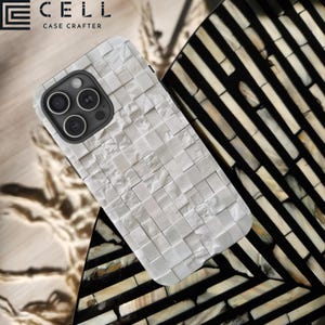 May include: A white phone case with a textured, tiled design. The case is made by the company "CELL CASE CRAFTERS".