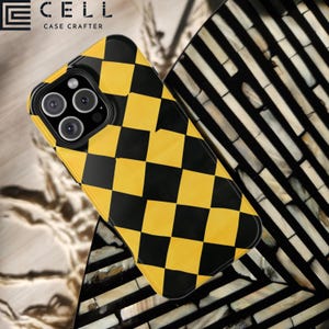 May include: A yellow and black checkered phone case with multiple camera lenses. The phone case is made by Case Crafter. The case is on a decorative surface with black and white stripes.
