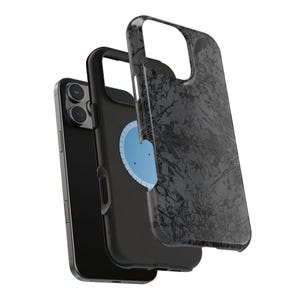 May include: Black smartphone with a protective case. The case has a dark gray floral pattern. The phone is black with three camera lenses. A light blue circle is visible on the back of the phone.