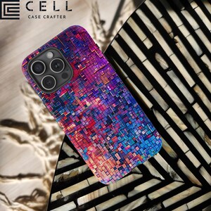 May include: A colourful phone case with a geometric pattern of squares in shades of pink, blue, and purple. The case is designed for a phone with a triple camera lens.