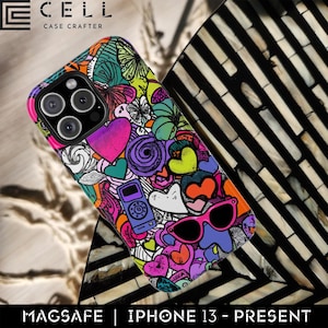 May include: A brightly coloured iPhone case with a design of hearts, flowers, and sunglasses. The case has a MagSafe feature and is for iPhone 13 and later models. The case is made by Cell Case Crafter.