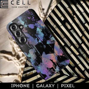 Pode incluir: Capa de telemóvel preta com um design de borboletas em tons de roxo, azul e rosa. A capa tem um acabamento brilhante e o texto "IPHONE | GALAXY | PIXEL" na parte inferior. A marca "CELL CASE CRAFTER" está no topo.