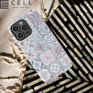 May include: A white iPhone case with a colorful geometric pattern. The case features a tiled design with shades of blue, pink, and gray. The case is made of durable plastic and is designed to protect your phone from scratches and drops. The case is compatible with the iPhone 13 Pro.