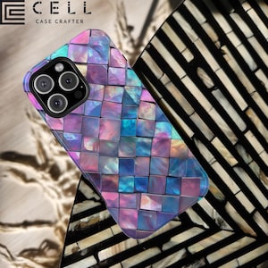 May include: A phone case with a mosaic design featuring iridescent blue, purple, and pink squares. The case is made of a hard plastic material and has a raised camera bump. The case is shown on a patterned surface.