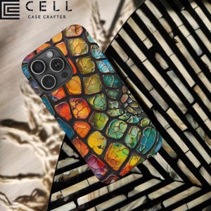 May include: A smartphone case with a colorful, mosaic-like design. The case features a pattern of irregular, multi-colored shapes in shades of red, orange, yellow, green, and blue. The case is on a black and white striped surface. The brand name "E CELL CASE CRAFTER" is visible.