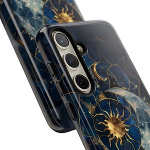 May include: A black phone case with a celestial design featuring a gold sun and moon on a blue and gold marbled background.