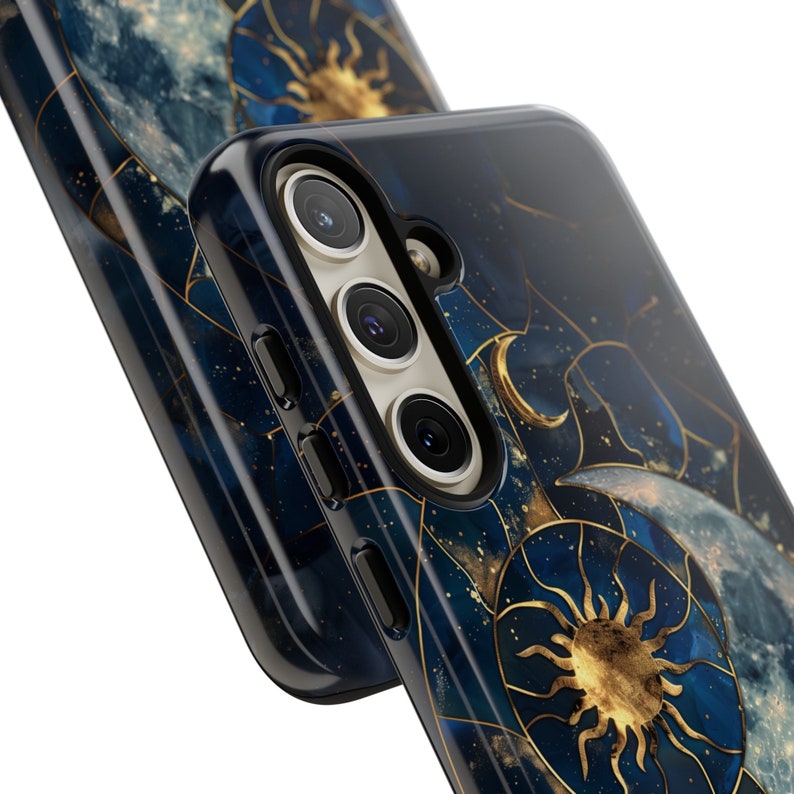 May include: A black phone case with a celestial design featuring a gold sun and moon on a blue and gold marbled background.