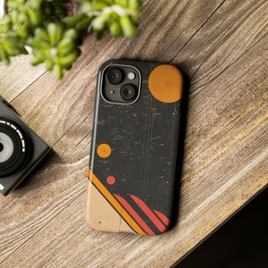 Peut inclure: Une coque de téléphone noire avec un motif géométrique aux accents orange, rouge et beige. La coque a un aspect vieilli avec une texture légèrement mouchetée.