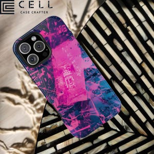 May include: A smartphone case with a vibrant abstract design in shades of pink and blue. The case features a dark blue border and a camera cutout. The text "CELL CASE CRAFTER" is visible in the upper left corner.