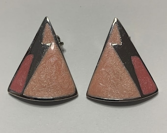 May include: A pair of silver tone earrings with a geometric design. The earrings are triangular shaped and have a pink and black enamel finish.