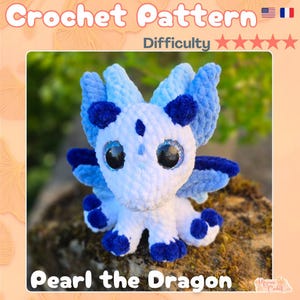 Peut inclure: Un dragon en crochet, blanc et bleu, avec de grands yeux brillants. Le dragon a des accents bleus sur ses ailes, ses pieds et sa tête. Le texte "Crochet Pattern" et "Pearl the Dragon" est inclus.