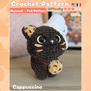 May include: A dark brown crochet cat plushie with large black eyes, a small pink nose, and tan whisker markings. The cat wears a white textured hat and holds a tan cookie with brown chocolate chips. Text reads Crochet Pattern, Myoucat, Cappuccino.