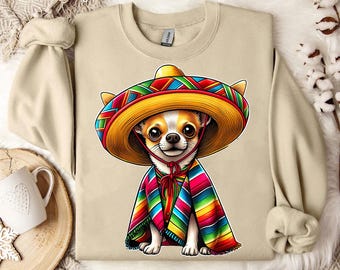 Puede incluir: Una sudadera de color canela con un chihuahua que lleva un sombrero de colores y una capa de rayas. El perro está mirando a la cámara. La sudadera tiene cuello redondo y mangas largas.
