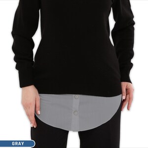 Puede incluir: Un extensor de camisa gris con dos botones es visible debajo de un suéter negro. El extensor está diseñado para agregar longitud a una parte superior. La palabra "GRAY" está en un cuadro azul en la parte inferior.