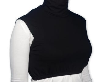 May include: A black turtleneck dickey, a garment designed to be worn under other clothing. The dickey has a high, close-fitting collar and covers the upper chest and shoulders. The bottom edge is elasticated. The dickey is shown over a white long-sleeved shirt.