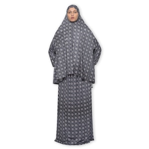 May include: A long, black and white floral print prayer dress with long sleeves and a matching headscarf.