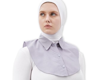 May include: A light grey collared shirt with a white undershirt and a white hijab. The shirt has a button-up front and a rounded collar.