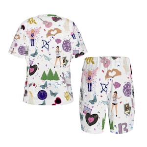 May include: White t-shirt and shorts set with a repeating pattern of musical instruments, butterflies, and figures. The shorts have a matching design. The set is made of a soft, comfortable material.