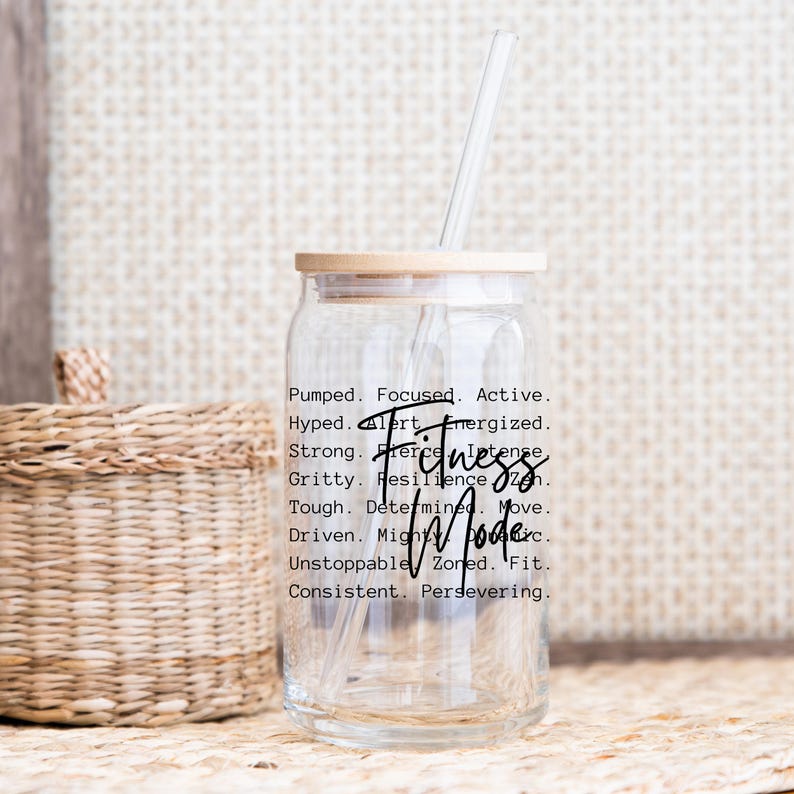 May include: A clear glass tumbler with a bamboo lid and a clear straw. The tumbler has the words "Fitness Mode" in a handwritten font, along with motivational words. The tumbler is designed for fitness enthusiasts.