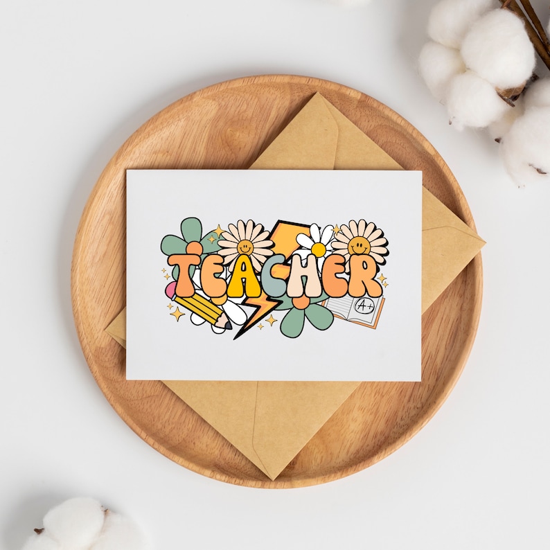 May include: A white card with the word "TEACHER" in colorful, stylized letters surrounded by flowers, a pencil, a lightning bolt, and a book with an A+ grade. The card is on a brown wooden plate.