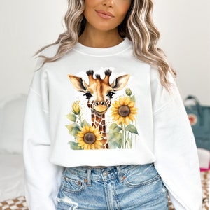 May include: White sweatshirt featuring a watercolour illustration of a giraffe with sunflowers. The giraffe is looking at the viewer and has a brown and yellow spotted pattern.