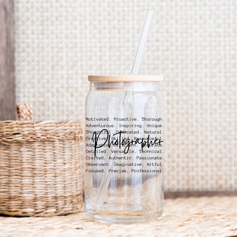 May include: A clear glass bottle with a wooden lid and a straw. The bottle has the words "Motivated. Proactive. Thorough. Adventurous. Inspiring. Unique. Thoughtful. Dedicated. Natural. Creative. Skilled. Resourceful. Adaptable.  Photographer. Detailed. Versatile. Technical. Crafted. Authentic. Passionate. Observant. Imaginative. Artful. Focused. Precise. Professional." printed on the side.