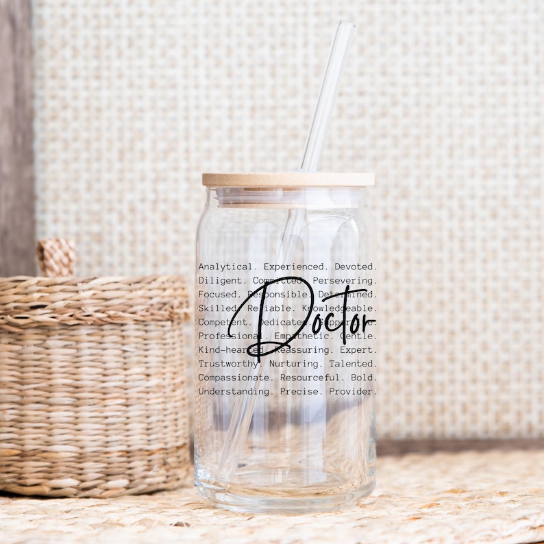 May include: A clear glass water bottle with a bamboo lid and a straw. The bottle has a black and white design with the word "Doctor" and a list of positive attributes.