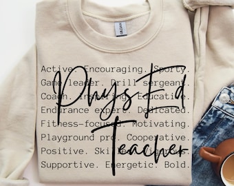 May include: A beige sweatshirt with the text "Phys Ed Teacher" in black lettering. The text is surrounded by a list of words describing the qualities of a physical education teacher, such as "active", "encouraging", "sporty", "game leader", "drill sergeant", "coach", "inspiring", "educative", "endurance expert", "dedicated", "fitness-focused", "motivating", "playground pro", "cooperative", "positive", "skillful", "supportive", "energetic", and "bold".
