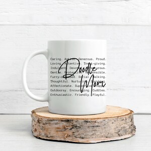 May include: White ceramic coffee mug with a black and white graphic design. The text reads "Doodle Mom" and lists a series of adjectives describing a doodle dog.