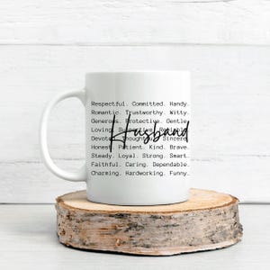 May include: A white ceramic mug with the word "Husband" in a handwritten font. The mug is printed with a list of positive adjectives such as "respectful," "romantic," and "loyal." The mug sits on a wooden coaster.