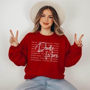 May include: Red sweatshirt with white text that reads "Doodle Mom" and a definition of the word "Doodle Mom" including words like caring, active, generous, proud, loving, attentive, and playful.