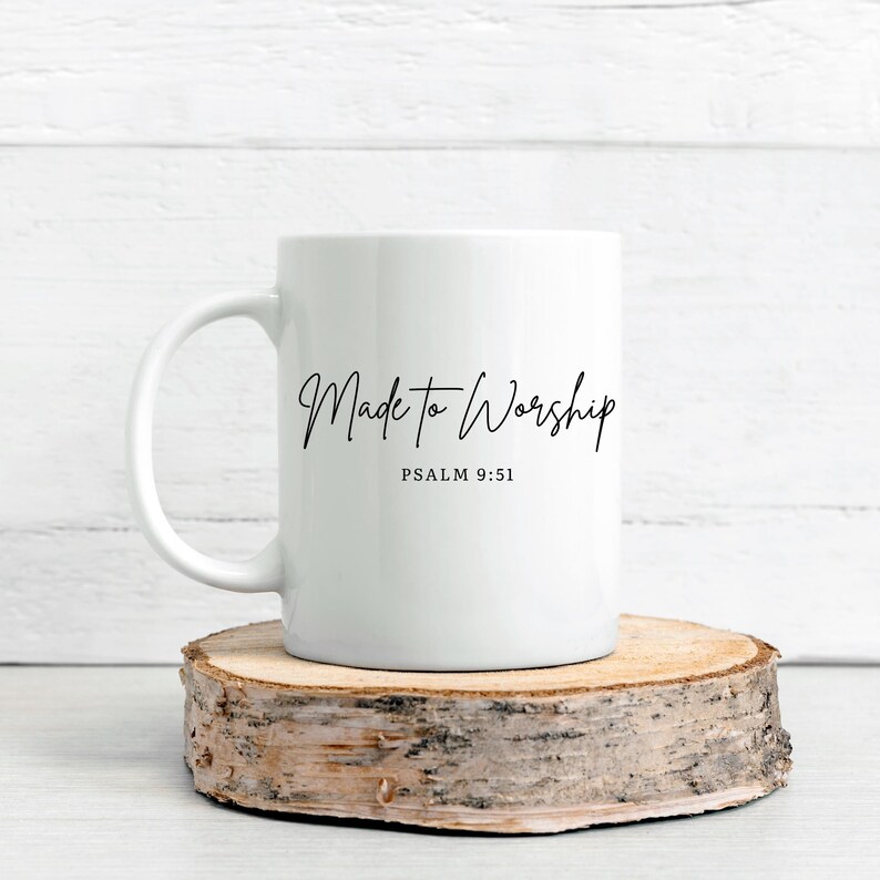 May include: White ceramic mug with the text "Made to Worship" and Psalm 9:51 printed in black script. The mug is displayed on a round, natural wood slice, set against a white wooden background.