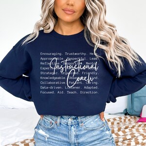 May include: A navy blue sweatshirt with white text. The text includes the words "Instructional Coach" and a list of descriptive words such as "Encouraging," "Trustworthy," and "Supportive."