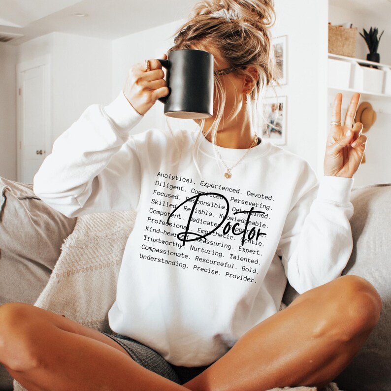 May include: White sweatshirt with the word "Doctor" in bold text surrounded by a list of positive attributes, such as "analytical", "experienced", "devoted", "reliable", "knowledgeable", "compassionate", and "resourceful".