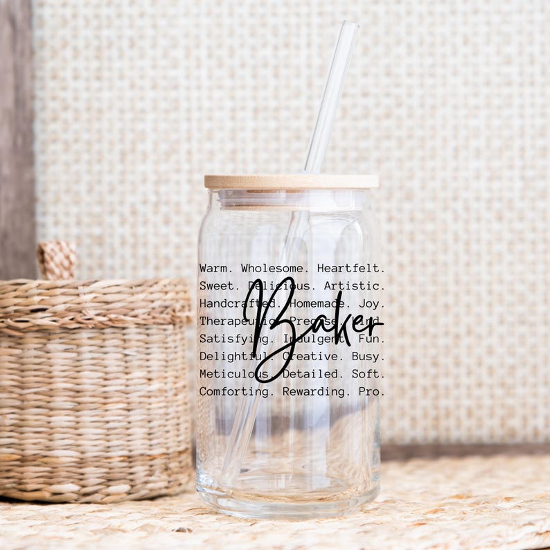 May include: A clear glass jar with a wooden lid and a glass straw. The jar has a label with the word "Baker" and a list of words describing the qualities of a baker, such as "warm", "wholesome", "heartfelt", "sweet", "delicious", "artistic", "handcrafted", "homemade", "joy", "therapeutic", "precise", "satisfying", "indulgent", "fun", "delightful", "creative", "busy", "meticulous", "detailed", "soft", "comforting", "rewarding", and "pro".