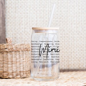 May include: A clear glass tumbler with a wooden lid and a straw. The tumbler has the word "Mimi" written on it in black lettering, along with a list of positive adjectives describing the person named Mimi.