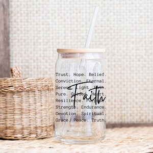Puede incluir: Una botella de agua de vidrio transparente con una tapa de madera y una pajita. La botella tiene la palabra "Fe" escrita en letras grandes, y una lista de palabras asociadas con la fe, como "confianza", "esperanza", "creencia", "convicci&oacute;n", "eterno", "sereno", "luz", "camino", "puro", "guiado", "coraz&oacute;n", "resiliencia", "prop&oacute;sito", "fuerza", "resistencia", "devoci&oacute;n", "espiritual", "gracia", "paz" y "verdad".