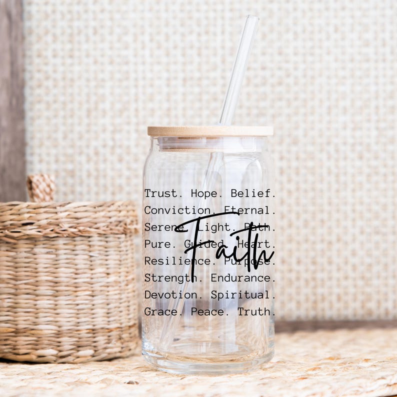 Puede incluir: Una botella de agua de vidrio transparente con una tapa de madera y una pajita. La botella tiene la palabra "Fe" escrita en letras grandes, y una lista de palabras asociadas con la fe, como "confianza", "esperanza", "creencia", "convicci&oacute;n", "eterno", "sereno", "luz", "camino", "puro", "guiado", "coraz&oacute;n", "resiliencia", "prop&oacute;sito", "fuerza", "resistencia", "devoci&oacute;n", "espiritual", "gracia", "paz" y "verdad".