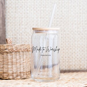 May include: Clear glass can-shaped tumbler with a bamboo lid and a clear straw. The words "Made to Worship" and "Psalm 9:51" are printed in black script on the front. A woven basket is in the background.