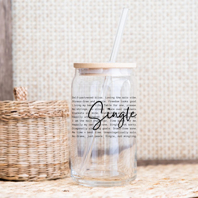 May include: A clear glass tumbler with a bamboo lid and a straw. The tumbler has a quote printed on it that reads "Self-partnered bliss. Loving the solo vibe. Stress-free and whole. Freedom looks good. Living my best life. Table for one, please. No strings, no stress. Peace over partners. Blankets are mine. Happily untethered. Single. Not sorry. I am the main character. Time for me. Happily my own -one. Single. Diagonally slaying goals. Drama-free zone. Me time, best time. Unapologetically solo. No drama, just peace. Single, not mingling."