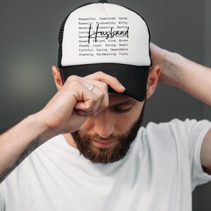 May include: A black and white trucker hat with the word "Husband" in a handwritten font. The hat's white front panel lists positive attributes like "Respectful," "Kind," and "Funny."